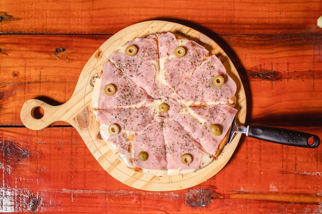 Vista aérea de una pizza de mozzarella con jamón en una mesa de madera