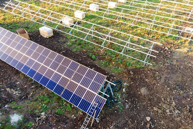 Vista aérea de la planta de energía solar en construcción en campo verde. Montaje de cuadros eléctricos para producción de energía ecológica limpia.