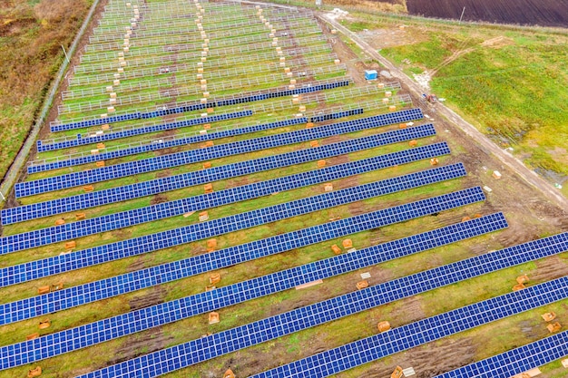 Vista aérea de la planta de energía solar en construcción en campo verde. Montaje de cuadros eléctricos para producción de energía limpia y ecológica.