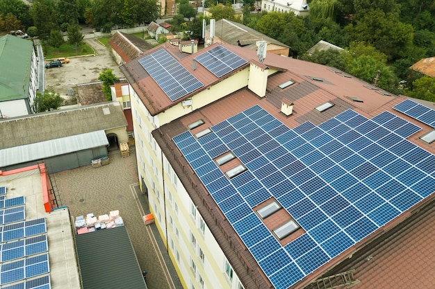 Vista aérea de la planta de energía solar con paneles fotovoltaicos azules montados en el techo del edificio de apartamentos.