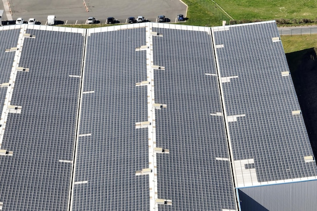 Vista aérea de la planta de energía solar con paneles fotovoltaicos azules montados en el techo de un edificio industrial para producir electricidad ecológica verde Producción del concepto de energía sostenible