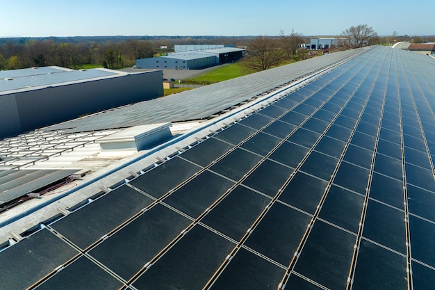 Vista aérea de la planta de energía solar con paneles fotovoltaicos azules montados en el techo de un edificio industrial para producir electricidad ecológica verde Producción del concepto de energía sostenible