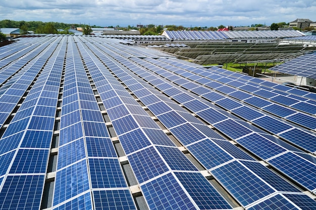 Vista aérea de la planta de energía solar con paneles fotovoltaicos azules montados en el techo de un edificio industrial para producir electricidad ecológica verde Producción del concepto de energía sostenible