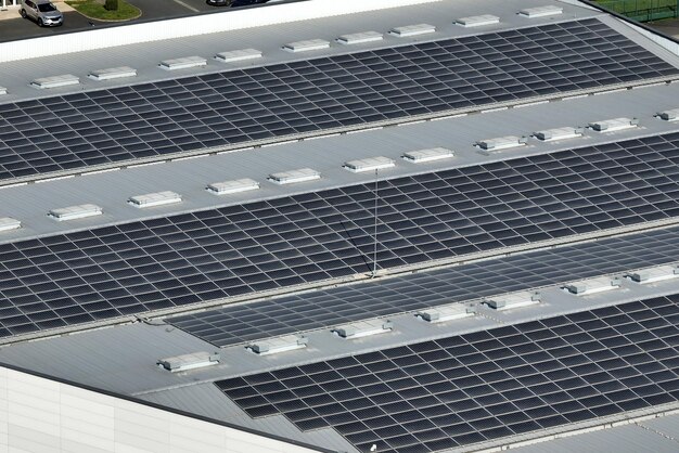 Vista aérea de la planta de energía solar con paneles fotovoltaicos azules montados en el techo de un edificio industrial para producir electricidad ecológica verde Producción del concepto de energía sostenible