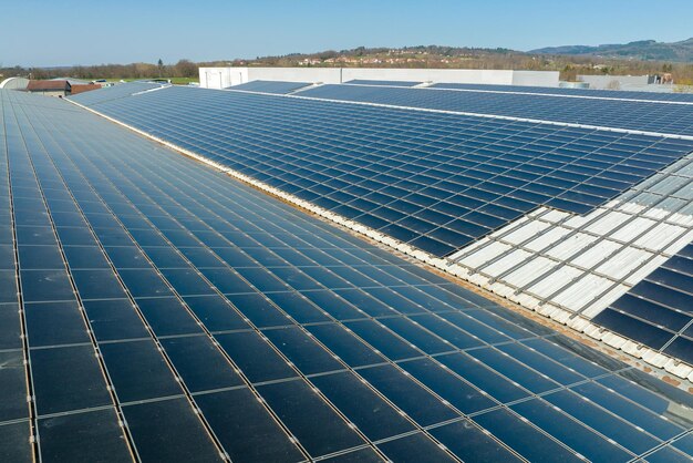 Vista aérea de la planta de energía solar con paneles fotovoltaicos azules montados en el techo de un edificio industrial para producir electricidad ecológica verde Producción del concepto de energía sostenible
