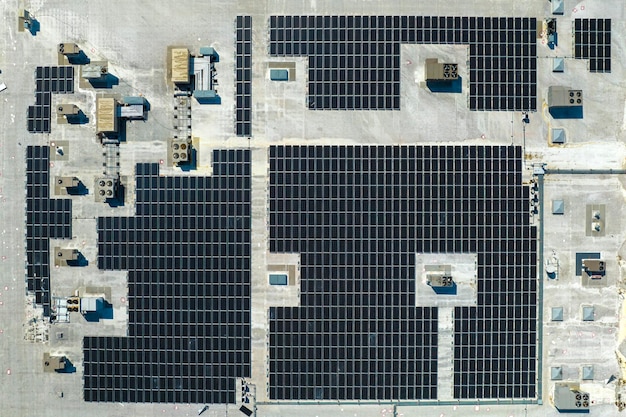 Vista aérea de la planta de energía solar con paneles fotovoltaicos azules montados en el techo de un edificio industrial para producir electricidad ecológica verde Producción del concepto de energía sostenible