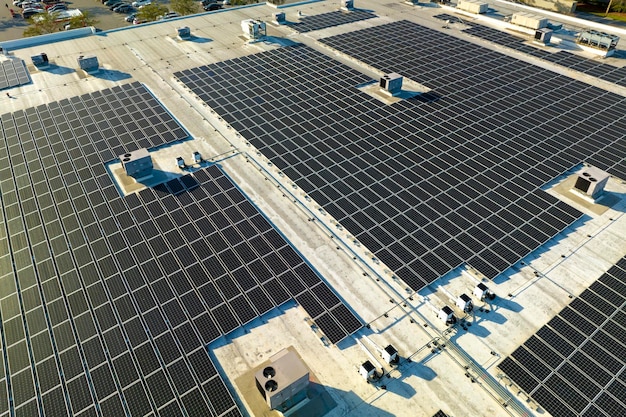 Vista aérea de una planta de energía solar con paneles fotovoltaicos azules montados en el techo de un edificio industrial para producir electricidad ecológica verde Producción de un concepto de energía sostenible