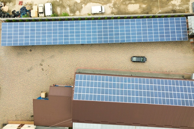 Vista aérea de la planta de energía solar con paneles fotovoltaicos azules montados en el techo del edificio industrial.