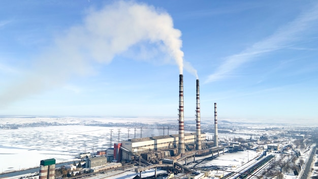 Vista aérea de la planta termoeléctrica con grandes chimeneas en un paisaje rural en invierno