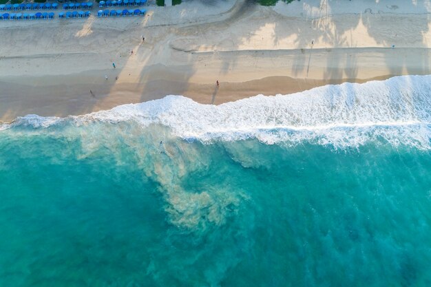 Vista aérea playa de arena y olas Hermoso mar tropical en la mañana imagen de temporada de verano por vista aérea drone shot, vista de ángulo alto de arriba hacia abajo.