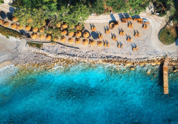 Vista aérea de la playa de arena con sombrillas árboles verdes al atardecer en verano Laguna azul en Oludeniz Turquía Paisaje tropical con agua azul transparente de la bahía del mar Vista superior desde drone Naturaleza