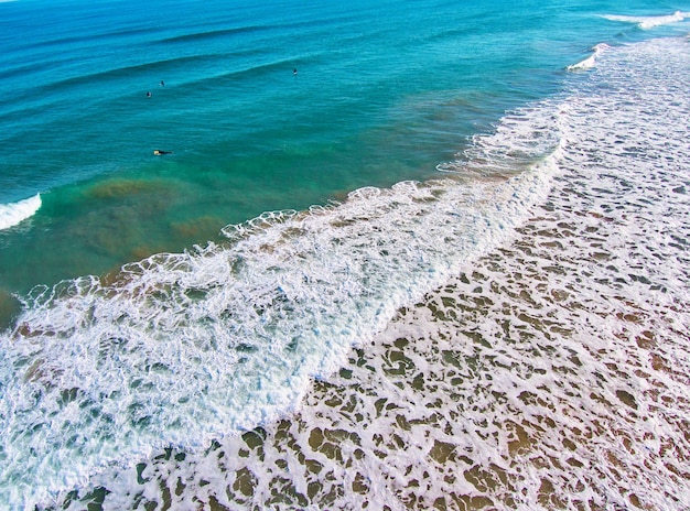 Vista aérea de una playa mediterránea con surfistas esperando las olas