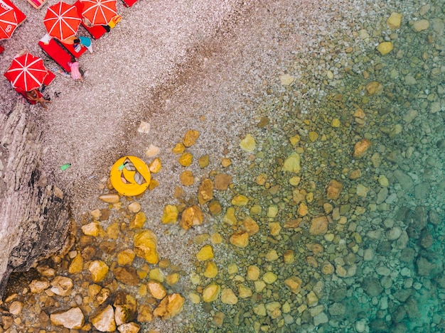 Vista aérea de la playa con tumbonas y sombrillas anillo inflable amarillo con sonrisa
