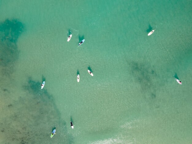 Vista aérea por drone de pessoas praticando Stand Up Paddle ou SUP no mar turquesa do Mediterrâneo.