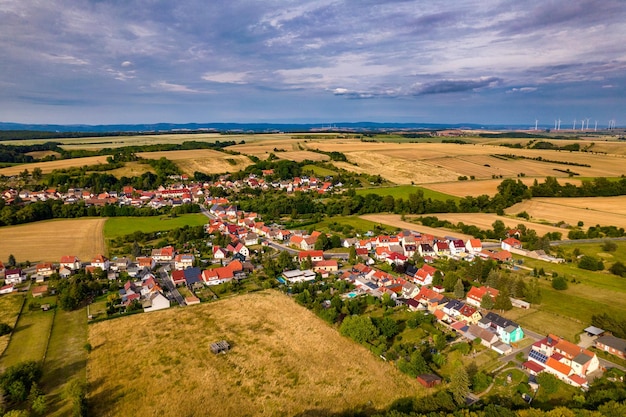 Vista aérea de un pueblo alemán rodeado de prados, tierras de cultivo y bosques en Alemania