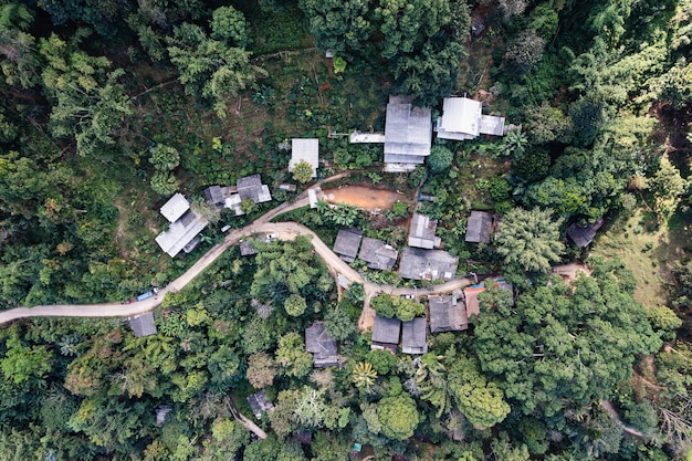 Vista aérea del pueblo rural local con camino de ripio a través del valle en el campo lejano entre la selva tropical en el sudeste asiático