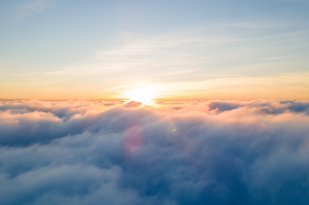 Vista aérea de la puesta de sol de color amarillo brillante sobre densas nubes blancas con sobrecarga de cielo azul.