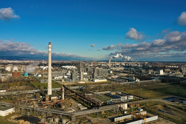 Vista aérea de la refinería de petróleo con tubos de transporte y chimeneas humeantes