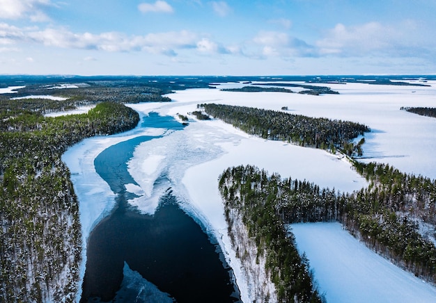 Vista aérea del río de invierno nevado con bosque verde en Finlandia