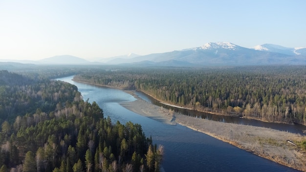 Vista aérea del río de montaña en el bosque de taiga a principios de la primavera al atardecer Paisaje siberiano o canadiense desde arriba