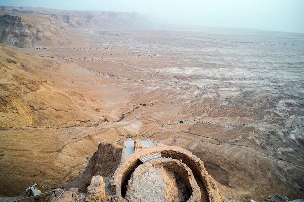 Foto vista aérea de las ruinas de la fortaleza del rey herodes contra el valle a los pies de las colinas en el desierto de judea israel restos de antiguos edificios humanos en la meseta de la montaña cerca de la orilla del mar muerto fuerte de masada