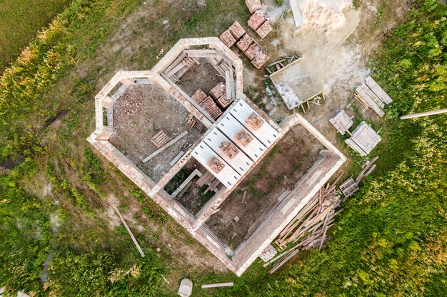 Vista aérea del sitio de construcción para la futura casa, piso de sótano de ladrillo y pilas de ladrillo para la construcción.