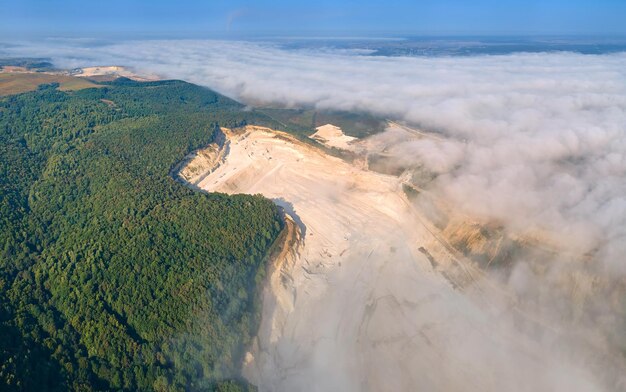 Vista aérea del sitio de minería a cielo abierto de extracción de materiales de piedra caliza para la industria de la construcción con excavadoras y volquetes.