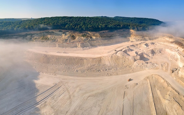 Vista aérea del sitio de minería a cielo abierto de extracción de materiales de piedra caliza para la industria de la construcción con excavadoras y volquetes