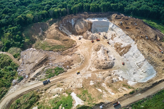 Vista aérea del sitio de minería a cielo abierto de materiales de piedra caliza para la industria de la construcción con excavadoras y camiones volquete