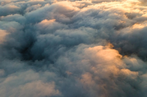 Vista aérea sobre a superfície de nuvens densas brancas ao pôr do sol