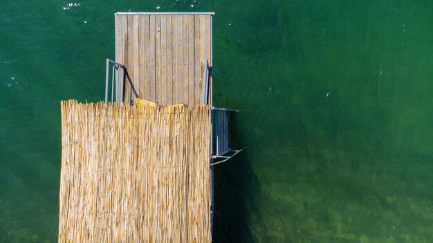 Vista aérea sobre el muelle del lago de agua verde con techo de madera