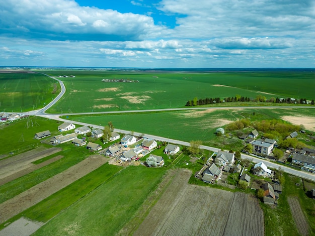 Vista aérea sobre un pequeño pueblo cerca de un camino de tierra Grandes campos multicolores plantados con varios cultivos agrícolas Campo de trigo desde la vista de un pájaro