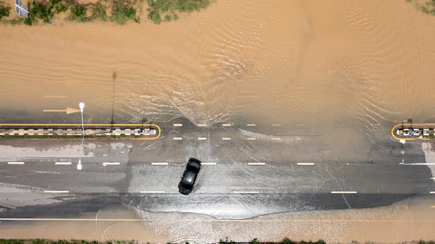 Vista aérea superior de la aldea inundada y la carretera rural con coche, vista desde arriba tomada por drone