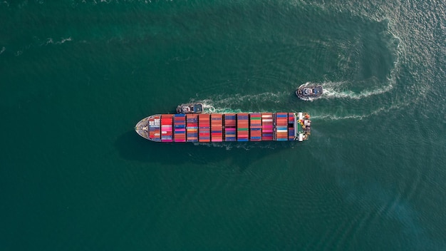 Vista aérea superior de un buque de carga que transporta un contenedor con un remolcador y se ejecuta para exportar mercancías desde el puerto del patio de carga hasta el envío de carga de concepto oceánico personalizado por barco