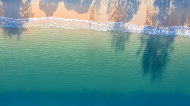 Vista aérea superior da praia com sombra água azul esmeralda e espuma de onda no mar tropical