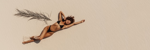 Foto vista aérea superior do zangão de mulher de biquíni maiô relaxante e banhos de sol na praia