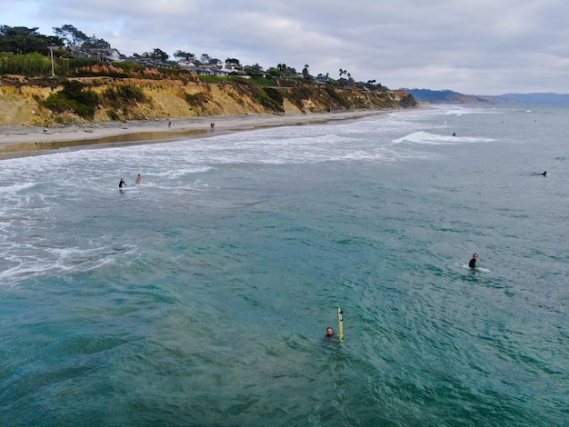 Vista aérea superior dos surfistas esperando as ondas na água azul. Del Mar Beach, Califórnia, EUA.