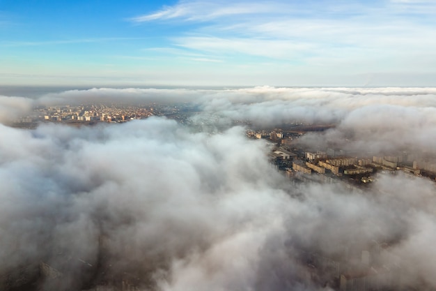 Vista aérea superior de esponjosas nubes blancas sobre la ciudad moderna con edificios de gran altura.