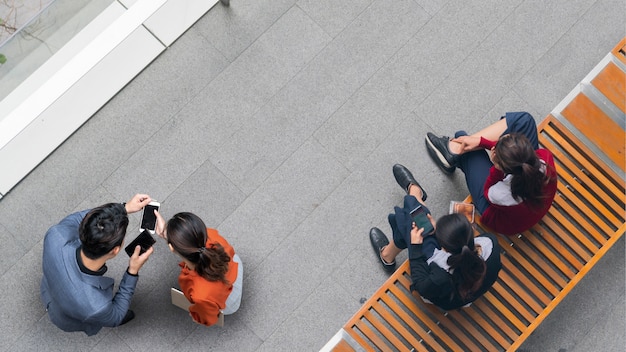Foto vista aérea superior de personas de negocios y mujeres que se encuentran y usan el teléfono inteligente para la presentación en la calle peatonal y dos niñas se sientan en el banco.