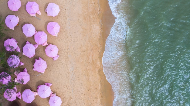 Vista aérea superior en la playa de arena. Sombrillas rosas