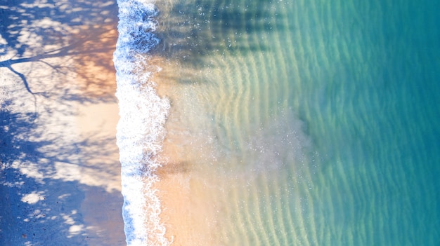 Vista aérea superior, playa con sombra de agua azul esmeralda y espuma de ola en el mar tropical