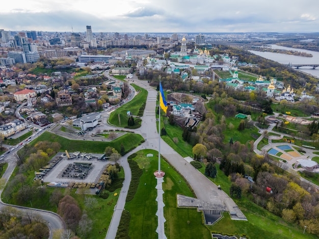 Vista aérea superior por drone da bandeira ucraniana balançando ao vento contra a cidade de kyiv ucrânia