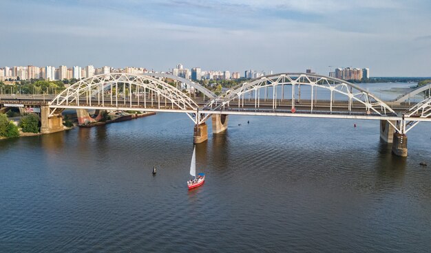 Vista aérea superior del puente darnitsky, yates y barcos que navegan en el río dnieper