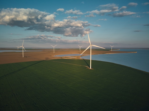 Vista aérea superior de turbinas eólicas y campo agrícola cerca del mar al atardecer