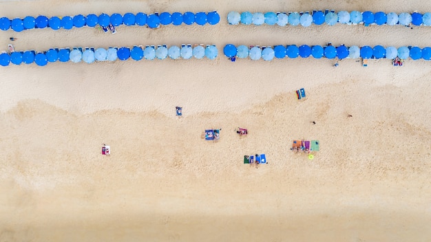 Vista aérea superior turistas que viajan durmiendo y relajarse en la playa de arena y sombrilla azul en la playa de Surin, Phuket, Tailandia