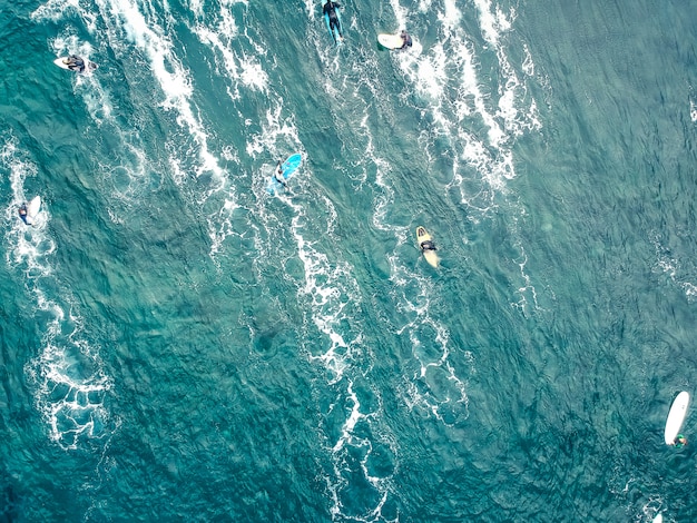 Vista aérea de surfistas en las aguas azules del fondo del océano Atlántico