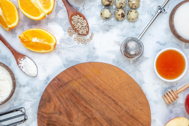 Vista aérea del tablero redondo de madera y los ingredientes para la comida saludable en la mesa azul blanca