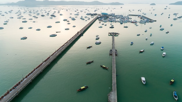 Vista aérea tiro de drone de cima para baixo do estacionamento de um iate e um veleiro na marina da baía de chalong