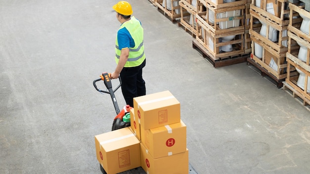 Vista aérea Trabalhadores de armazéns industriais asiáticos movendo mercadorias entre fileiras de prateleiras caixas embaladas Trabalhador de armazém descarregando mercadorias de paletes no armazenamento de armazéns usando com paleteira manual