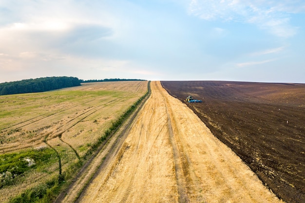 Vista aérea de un tractor arando el campo agrícola negro después de la cosecha a finales de otoño.